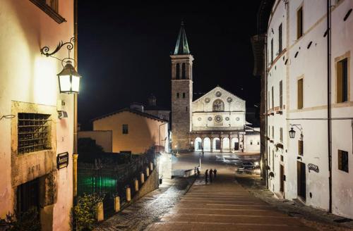 a city street at night with a church with a steeple at Torre Paola Dimora romantica in Acquasparta