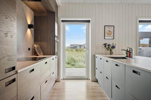 a kitchen with white cabinets and a sliding glass door at 341-Harboore-Gloryvej-27 in Harboør