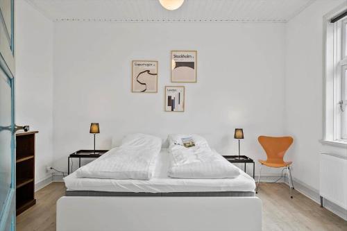 a white bedroom with a bed and two chairs at 713-Thyboron-Vesterhavsgade-34 in Thyborøn