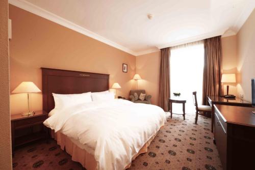 a hotel room with a large white bed and a window at LOTTE City Hotels Tashkent Palace in Tashkent