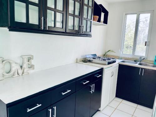 a kitchen with black and white cabinets and a sink at Apartments & Rooms in Cancun next to the beach in Cancún