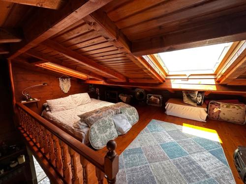 an attic bedroom with a bed and a large window at Tiny Maxi House in Hopa