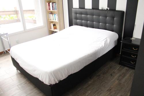 a bedroom with a large bed with a black headboard at Appartement moderne aux pieds des stations in Châtillon-sur-Cluses