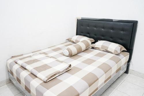 a bed with a black headboard and two pillows at Omah Seturan Homestay Jogja in Seturan