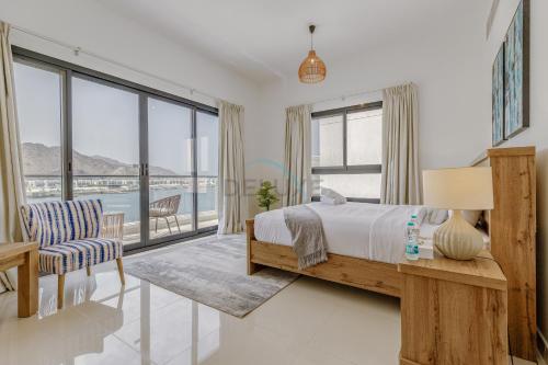 フジャイラにあるCoastal Escape with Private Pool, Breathtaking Sea And Mountain Views, Near Al Aqah Beach - Al Dana Island, Fujairah by Deluxe Holiday Homesのベッドと大きな窓のある寝室