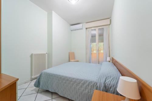 a white bedroom with a bed and a window at Green Village Accommodations in Colico