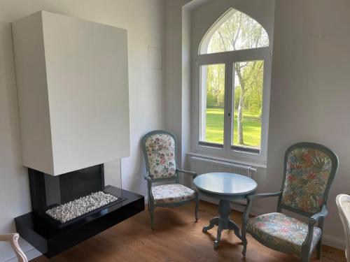 a living room with a table and chairs and a fireplace at Weisses Traumschloss An Der Ostsee Zwischen Zingst Und Rügen in Hohendorf