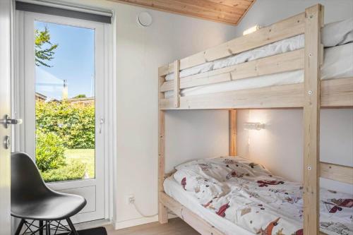 a bedroom with a bunk bed with a chair and a window at G245-Lemvig-Porsevej-45 in Lemvig