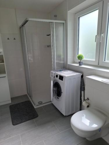 a bathroom with a toilet and a washing machine at De Hecksche Stuuv in Kreuztal