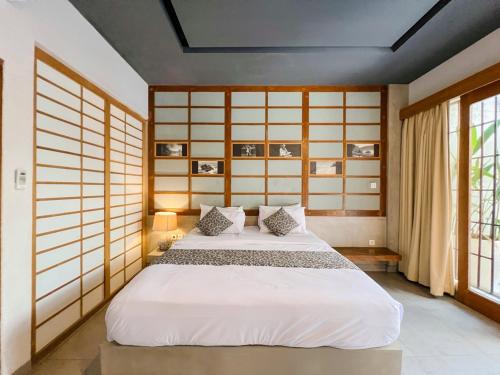un dormitorio con una cama con sábanas blancas en Apple Villa & Suite Seminyak, en Seminyak