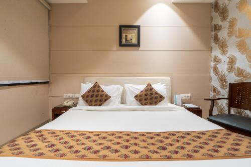 a bedroom with a white bed and a chair at Cosy Grand, Chanakyapuri by The Cosy Hotels in New Delhi