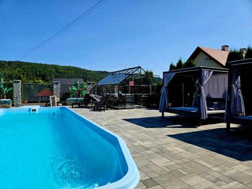 a swimming pool in a yard with a gazebo at Apartamenty pod Gromadzyniem in Ustrzyki Dolne