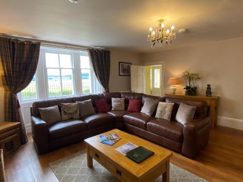 a living room with a leather couch and a coffee table at Balmeadowside Farmhouse with Hot Tub in Cupar