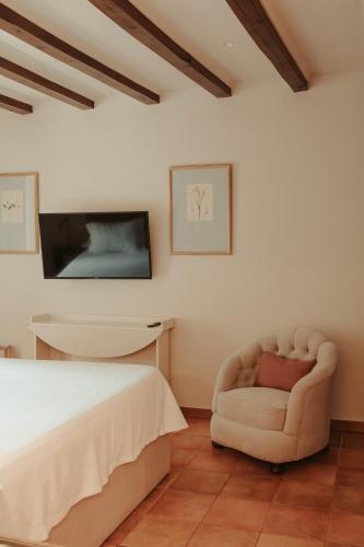a bedroom with a bed and a chair at Rondaia, a Winery & Fincahotel-Agroturismo in Tramuntana in Esporles