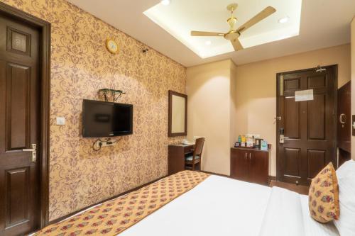 a bedroom with a bed and a tv on the wall at Cosy Grand, Chanakyapuri by The Cosy Hotels in New Delhi