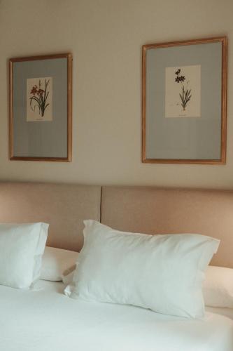 a bed with white pillows and two pictures on the wall at Rondaia, a Winery & Fincahotel-Agroturismo in Tramuntana in Esporles
