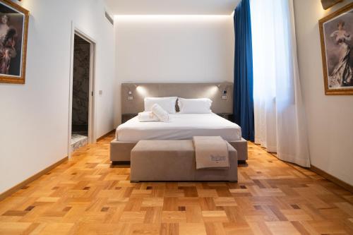 a bedroom with a large white bed and a ottoman at Duse Luxury Stay in Milan