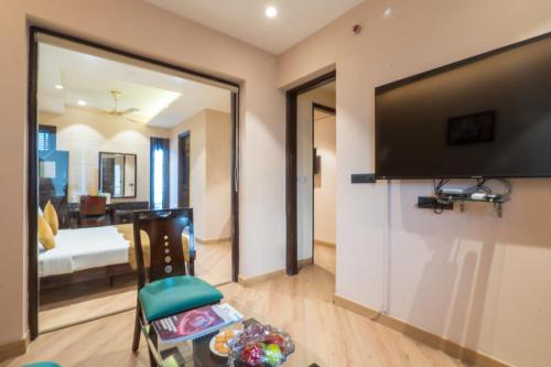 a living room with a large flat screen tv at Cosy Grand, Chanakyapuri by The Cosy Hotels in New Delhi