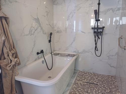 a white bathroom with a tub and a shower at De Witte Huis in Bethlehem