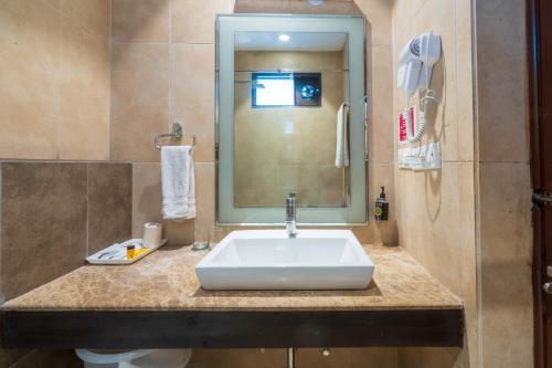 a bathroom with a sink and a mirror at Cosy Grand, Chanakyapuri by The Cosy Hotels in New Delhi