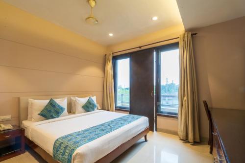 a bedroom with a bed and a large window at Cosy Grand, Chanakyapuri by The Cosy Hotels in New Delhi