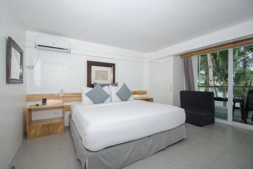 a white bedroom with a large white bed and a desk at Zuzuni Boutique Hotel in Boracay