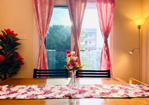 a vase of flowers on a table in front of a window at Evara Luxury Living Central 3BHK near HITEC City in Hyderabad