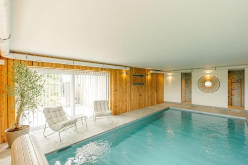 a large swimming pool with two chairs and a table at La Ferme d'Auwez - Arbre de vie - Gîte 4 pers avec piscines et sauna in Ciney