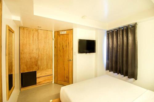 a small bedroom with a bed and a television at Zuzuni Boutique Hotel in Boracay