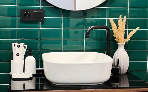 a bathroom with a white sink and a green tiled wall at Rooms Apart Hotel by RED in Yerevan