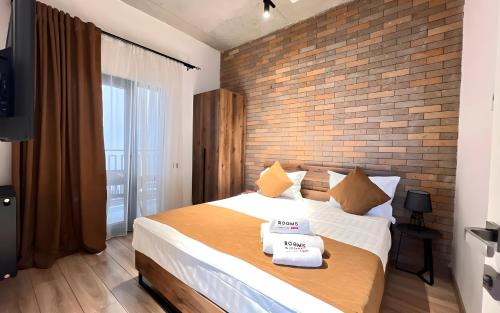 a bedroom with a large bed and a brick wall at Rooms Apart Hotel by RED in Yerevan