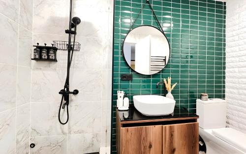 a bathroom with a sink and a shower with green tiles at Rooms Apart Hotel by RED in Yerevan