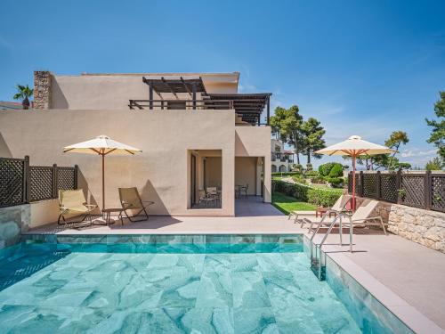a villa with a swimming pool and a house at Aegean Melathron Thalasso Spa Hotel in Kallithea Halkidikis