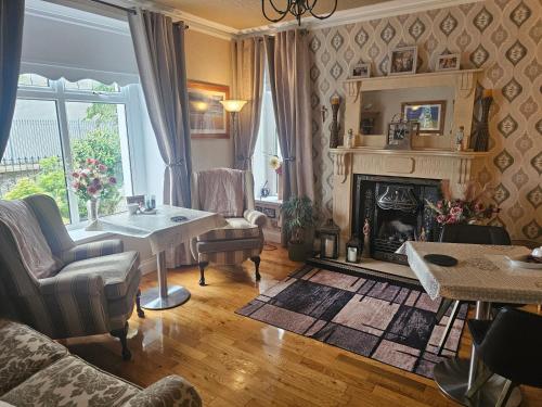 a living room with a fireplace and a table at Rose Park House in Derry Londonderry