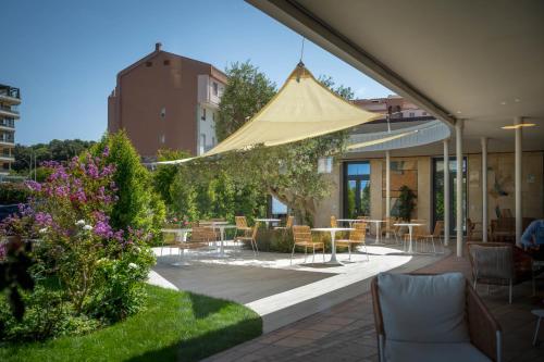 a patio with tables and chairs and a yellow umbrella at Hotel Carlo Felice Sassari in Sassari