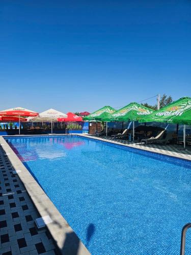 una grande piscina con ombrelloni e tavoli di Эко Парк a Bălţi
