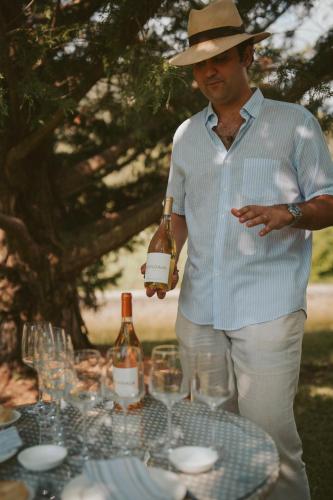 a man in a hat holding a bottle of wine at Rondaia, a Winery & Fincahotel-Agroturismo in Tramuntana in Esporles