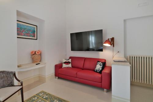 a red couch in a living room with a tv at Palazzo Rollo in Lecce