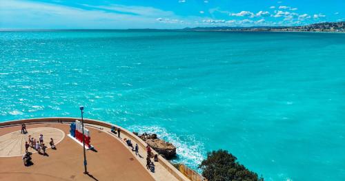 a group of people walking on the beach near the water at Hôtel La Pérouse Nice Baie des Anges in Nice