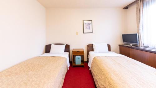 a hotel room with two beds and a flat screen tv at Business Hotel Takizawa Takasaki Station Nishiguchi in Takasaki
