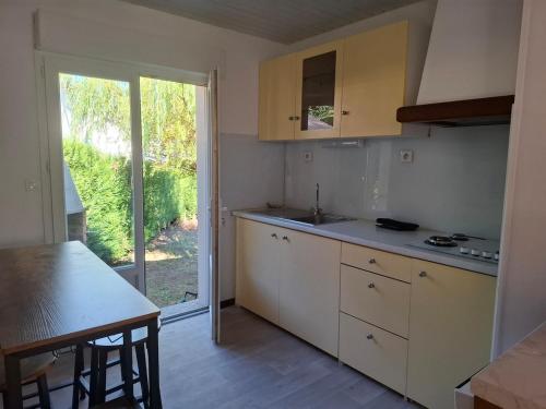 a kitchen with white cabinets and a table and a window at Maison de vacances in Lacaune