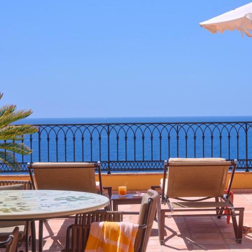 a patio with two tables and chairs and the ocean at Hôtel La Pérouse Nice Baie des Anges in Nice