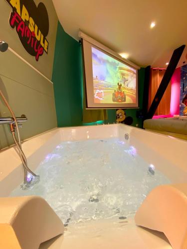 a jacuzzi tub in a room with a tv at Capsule Family - Sauna - Jacuzzi - Projecteur - Billard - Nintendo Switch 2 - Filet suspendu in Crespin
