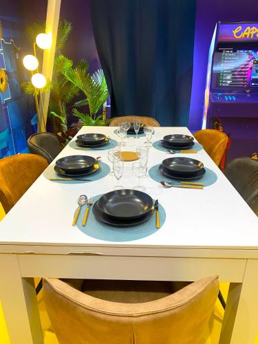 a white table with plates and glasses on it at Capsule Family - Sauna - Jacuzzi - Projecteur - Billard - Nintendo Switch 2 - Filet suspendu in Crespin