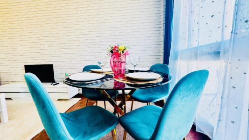 a table with blue chairs and a vase with flowers at Coeur de Dammarie - Balcon et Parking privé in Dammarie-lès-Lys