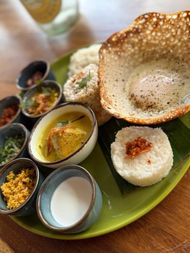 a green plate of food with a sandwich and dips at Daffodil Restaurant & Holiday Resort in Unawatuna