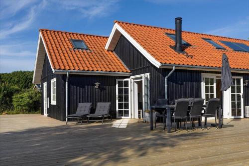 a black house with chairs and an orange roof at 16632-Farevejle-Karuphoj-4-C in Fårevejle