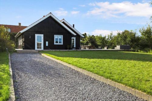 a black house with a gravel driveway at 16632-Farevejle-Karuphoj-4-C in Fårevejle