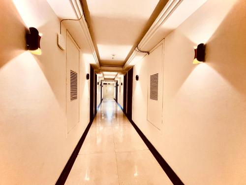 an empty corridor in a building with lights on the ceilings at Majesta stays pitampura in New Delhi