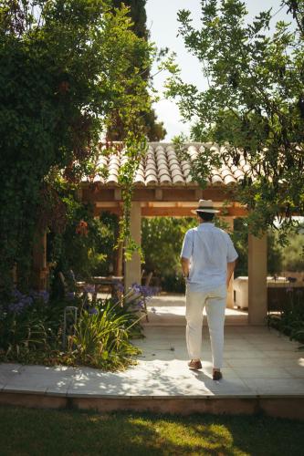 a man in a hat walking through a garden at Rondaia, a Winery & Fincahotel-Agroturismo in Tramuntana in Esporles